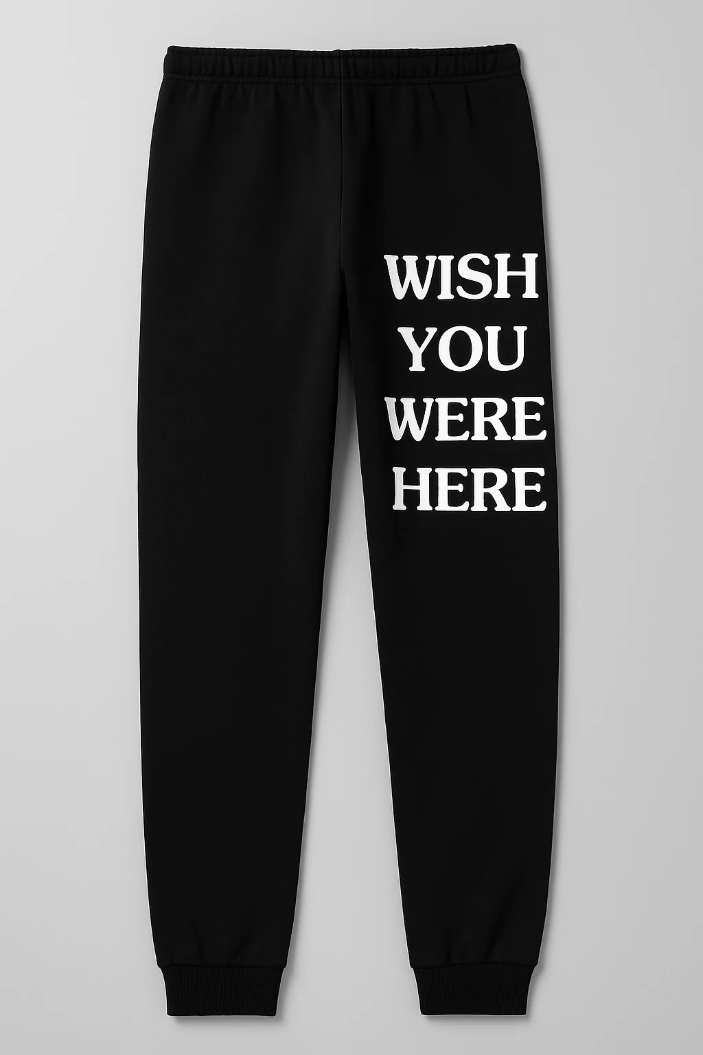 Person wearing “Wish You Were Here” jogger pants texting someone from a cozy city apartment at night.